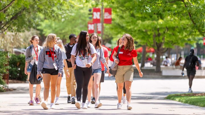 A group of students talk and walk across campus during New Student Enrollment event